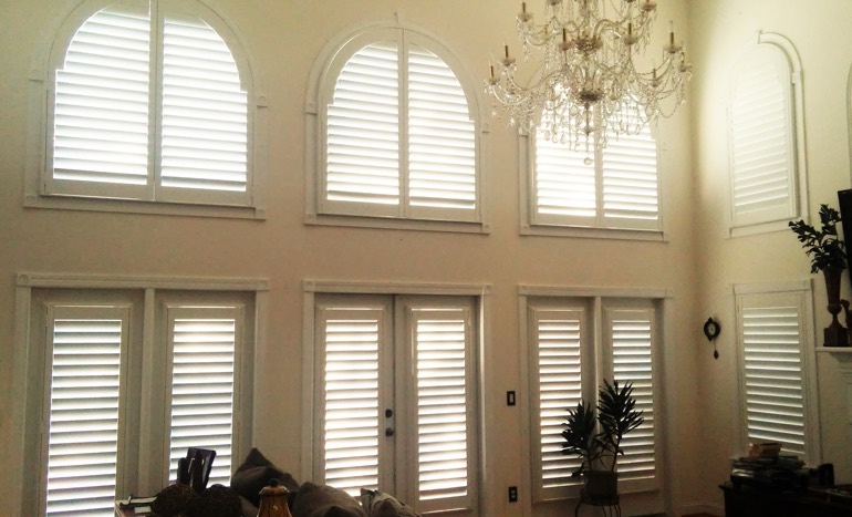 Television room in two-story Sacramento home with plantation shutters on high windows.