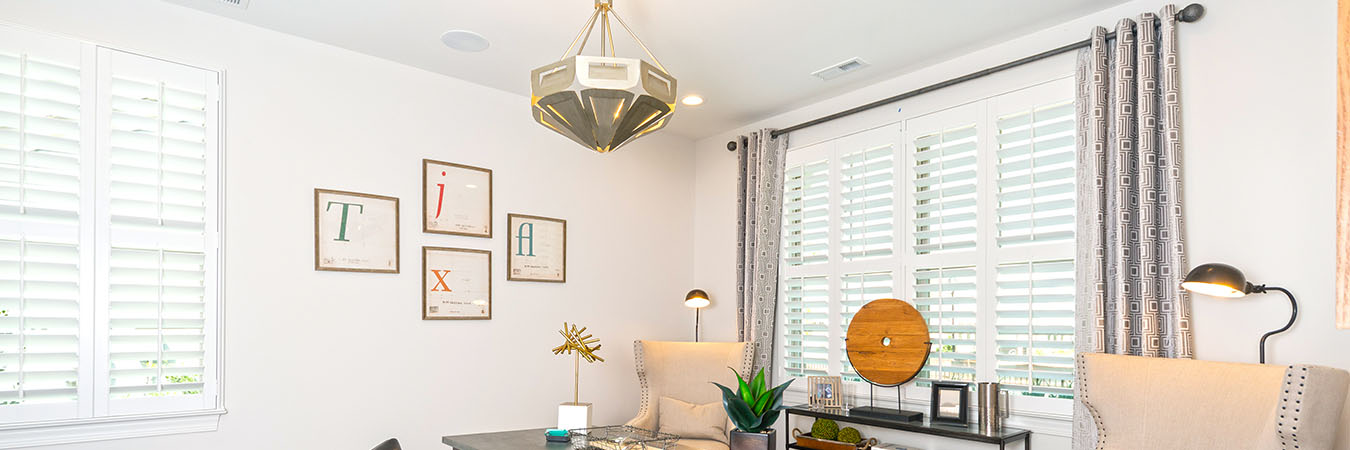 Large picture window with white Polywood shutters within an office setting.