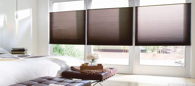 Minimal Sacramento bedroom with tall windows and brown honeycomb shades.