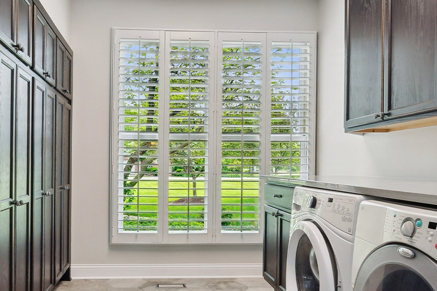 Find the perfect level of natural light for your Sacramento laundry room with interior shutters. White Polywood shutters letting light through a laundry room window