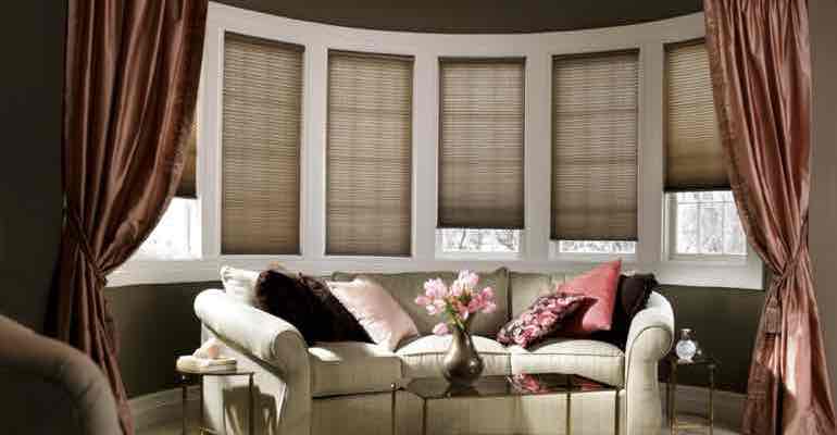 Vertical cellular shades in living room bow window.
