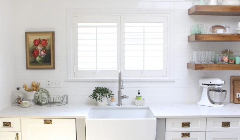 Plantation shutters over a farmhouse kitchen sink.