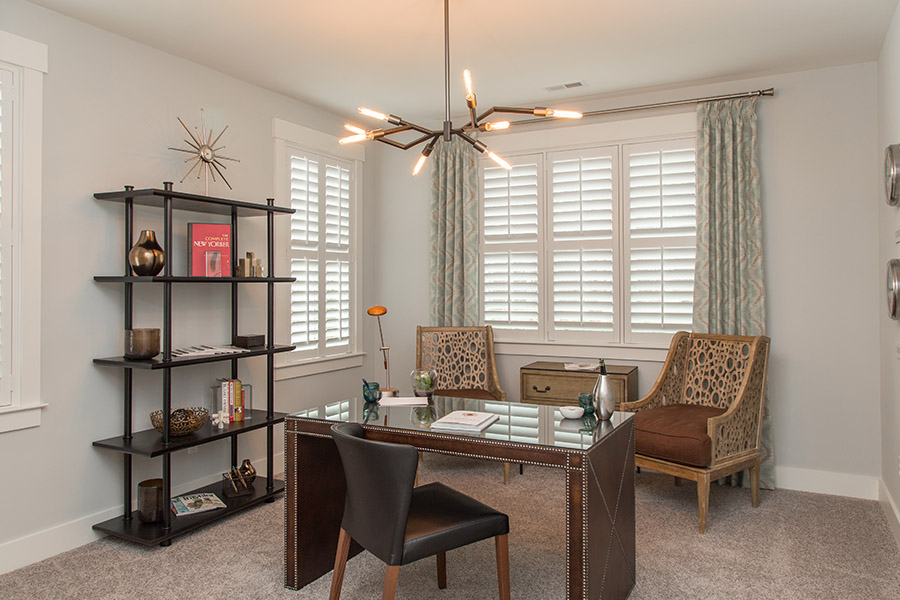 Colorful curtains can add a bit of flair with white Polywood shutters in Sacramento. Sage green patterned curtains on white polywood shutters in an office.