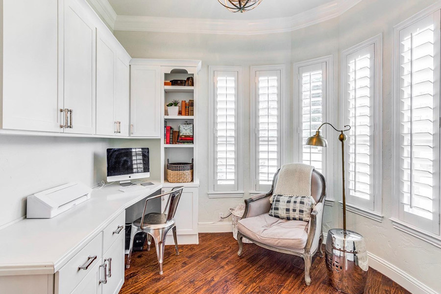 Enjoy comfortable temperatures with energy-efficient Polywood shutters in your home library. Bay windows with white Polywood shutters in an office/library setting.